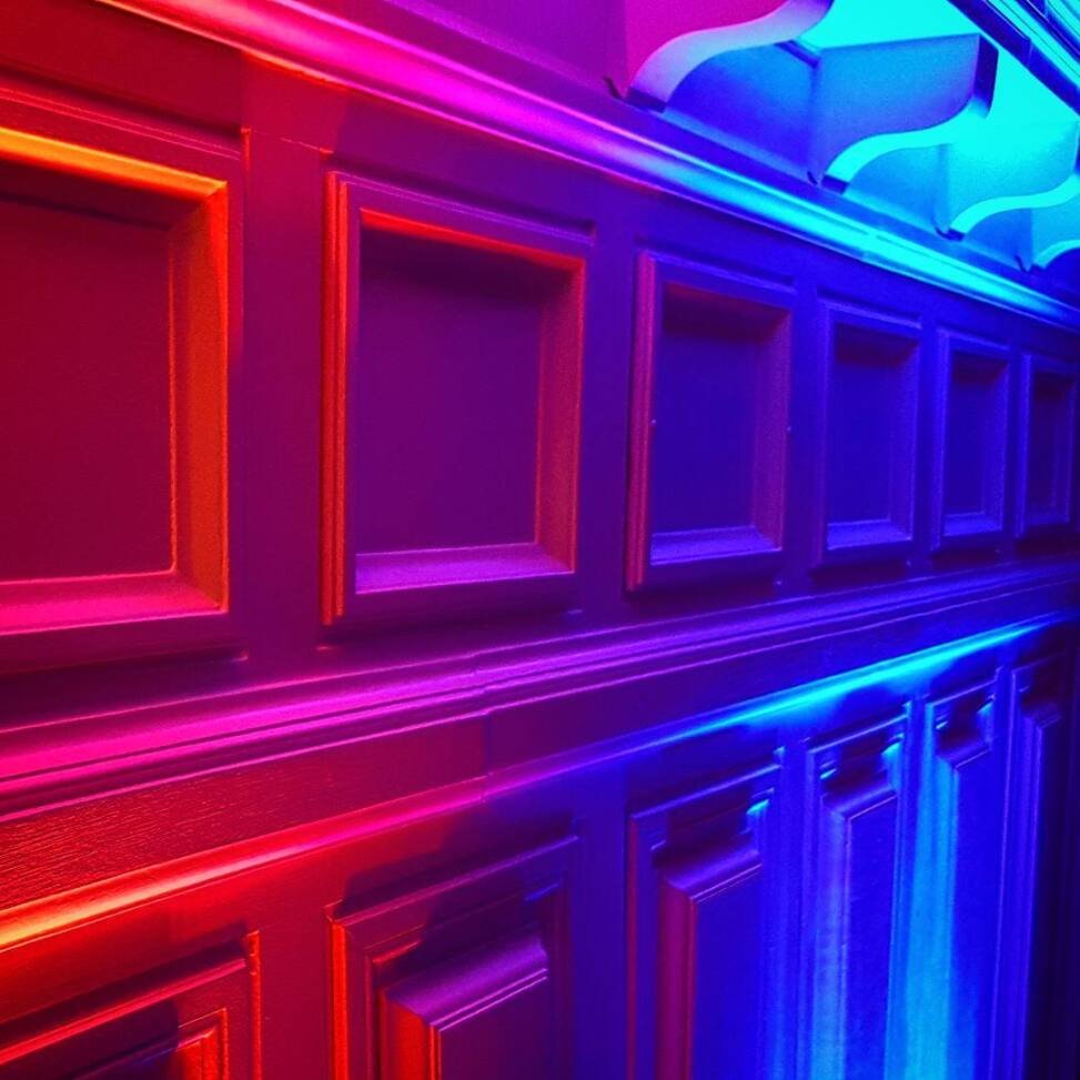 Rows of wooden wall panels washed in a gradient of red and blue neon light