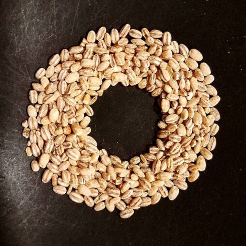 Ring of pearl barley grains arranged in a circle on a dark stone worktop