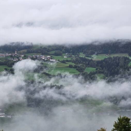 Hillside village and fields seen through drifting low cloud