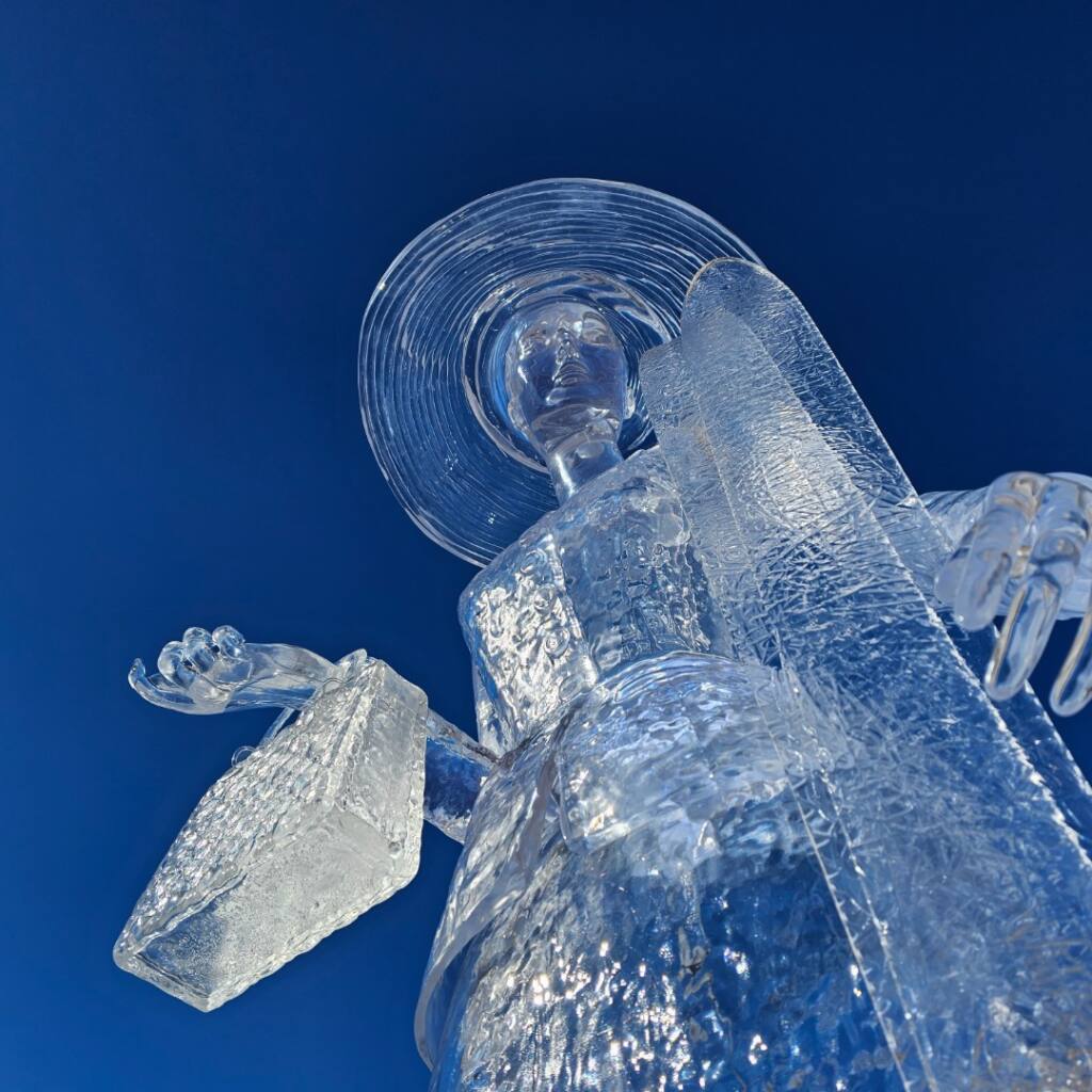 Transparent ice sculpture of an angel against a deep blue background