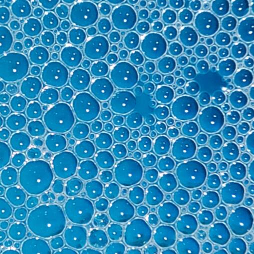 Close-up of clustered round bubbles on a bright blue surface