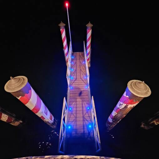 Illuminated tower and projected light patterns against a black night sky