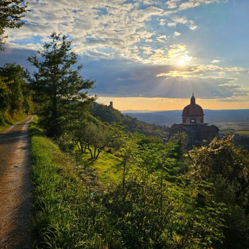 Gravel track running along a ridge towards a domed church at sunrise